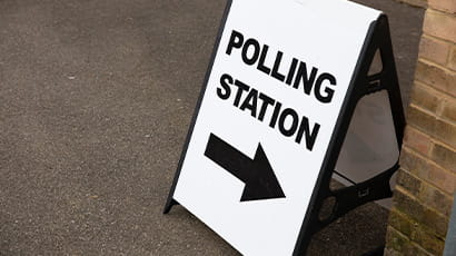 An A board advertising stand says Polling Station with an arrow giving directions
