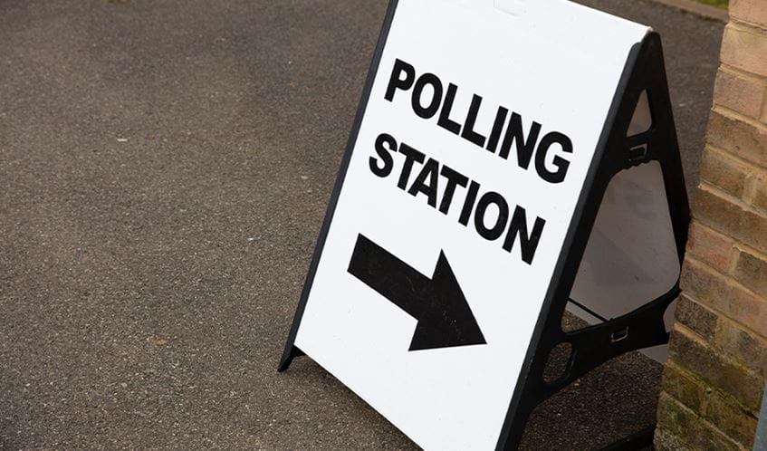 An A board advertising stand says Polling Station with an arrow giving directions