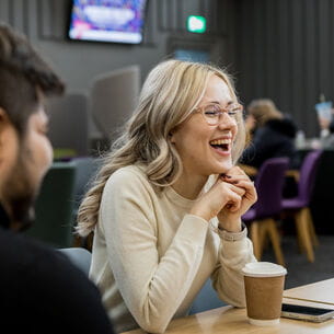 UWE Bristol staff member chatting and laughing with colleagues in the Atrium café.