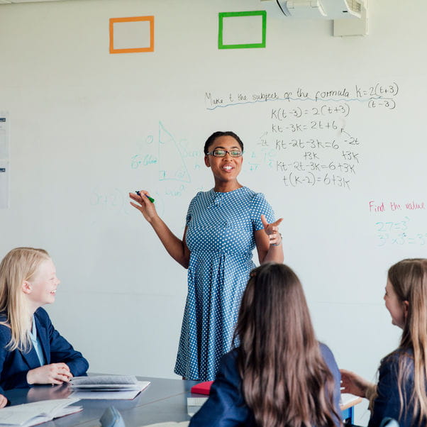 A female teacher in front of a whiteboard, teaching maths
