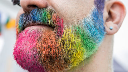 Closeup of someone's beard painted in rainbow colours at Bristol Pride.