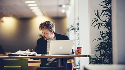 A student sat working on a laptop while having a coffee