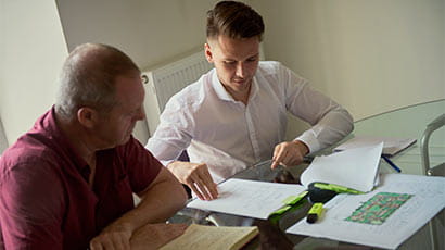 A middle-aged man and male student sat working together at a desk