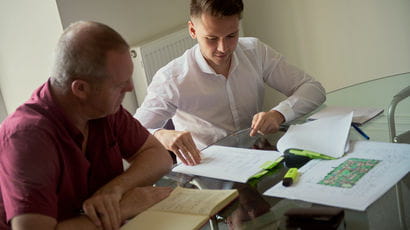 Student on placement at table with his mentor talking through a report.
