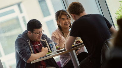 A group of students laughing around a table in OneZone.
