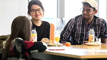 Three international students interacting over lunch