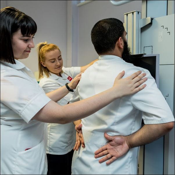Uniformed students using radiotherapy equipment.