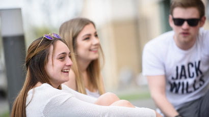 Three students chatting outside university accommodation