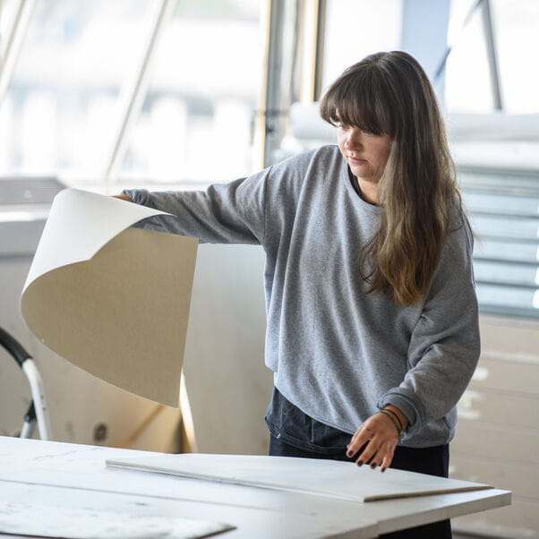 Student in the Drawing Studio preparing sheets of paper for a drawing class.