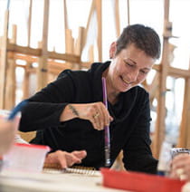 A person smiling with a paintbrush in hand.