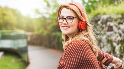 Red haired girl wearing headphones looking over shoulder and smiling