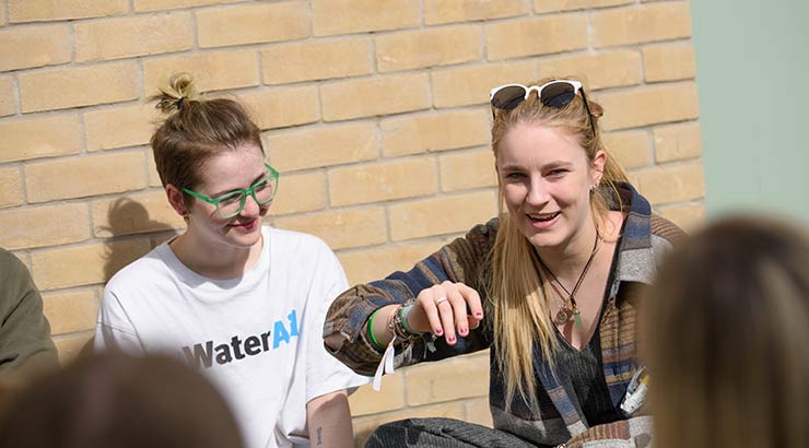 Two students chatting outside student accommodation in the sun