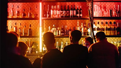 People standing at a bar in a nightclub ordering drinks