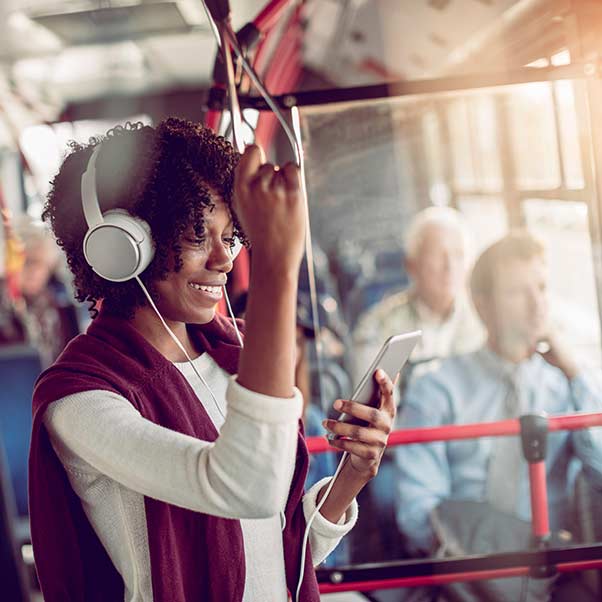 A woman on her phone with headphones on, whilst on a bus
