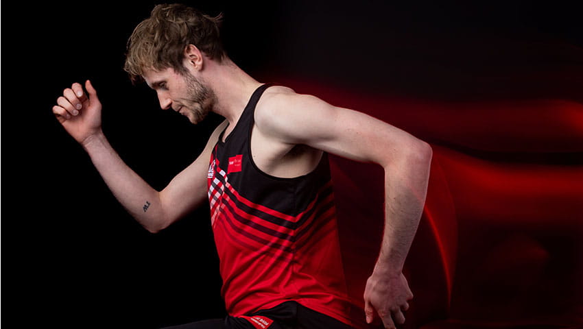 Man in running motion against a black background with red motion blurb behind indicating his movement forwards.