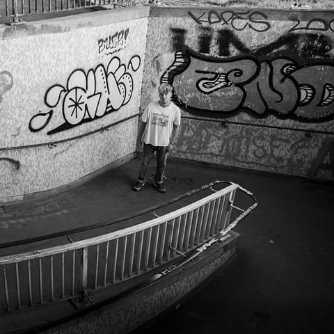 James Tombling short in black and white in front of graffitti and stairs.