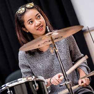 Student playing drums in a rehearsal space 