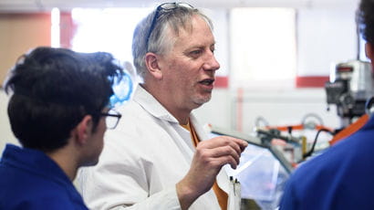 A lecturer in a lab talking to two students
