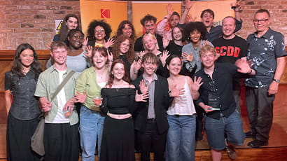 A group of celebrating students smile at the camera.