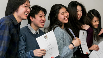 Group of international students holding certificates.