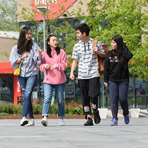 Four international students walking on Frenchay Campus