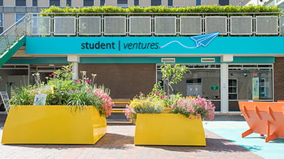 Exterior of the Student Ventures space entrance with bright orange concrete planters in front. 