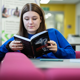 student reading a book in the Library