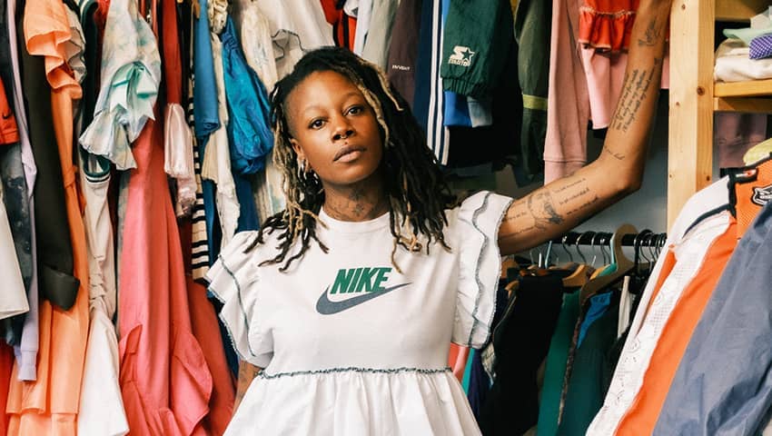 woman in a white dress standing in front of lots of clothes