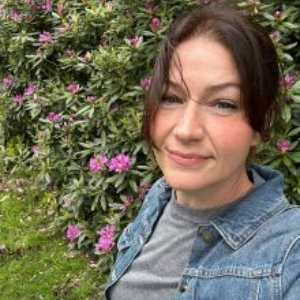 Headshot of Dr Jennifer Chubb with a background of green grass and pink flowers.