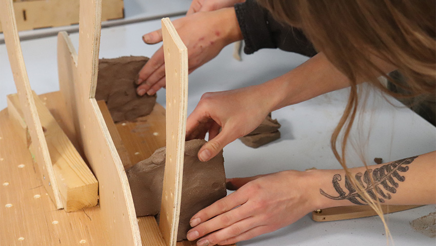 People moulding clay with their hands to create an art sculpture