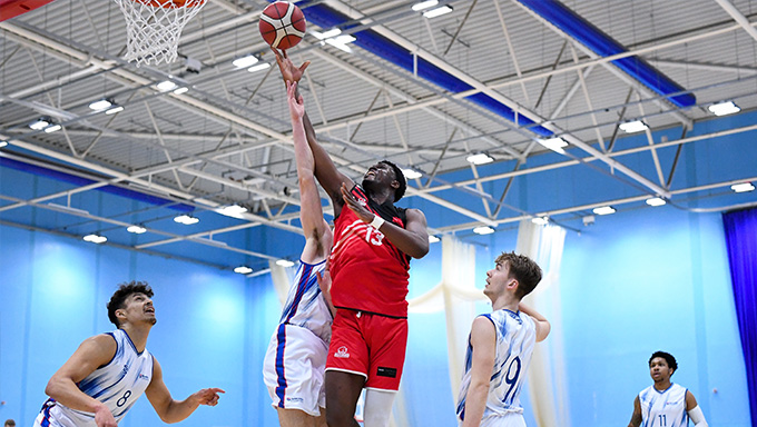 UWE Jets basketball player reaching for the hoop mid game.