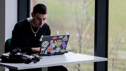 Student working on laptop decorated with bright stickers at City Campus