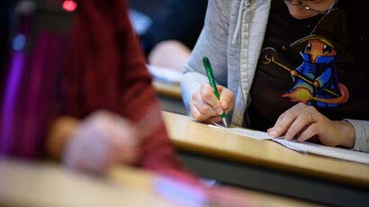 Close up of a student writing at a desk.