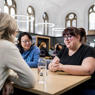 UWE Bristol staff seated in the Atrium café enjoying lunch together.