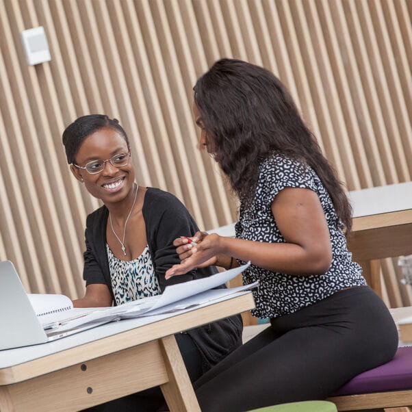 Two members of staff having a meeting at a table in the Atrium cafe.