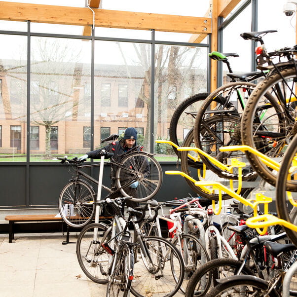 Member of staff locking up their bike in a bicycle park on campus.