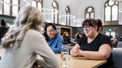 UWE Bristol staff seated in the Atrium café enjoying lunch together.