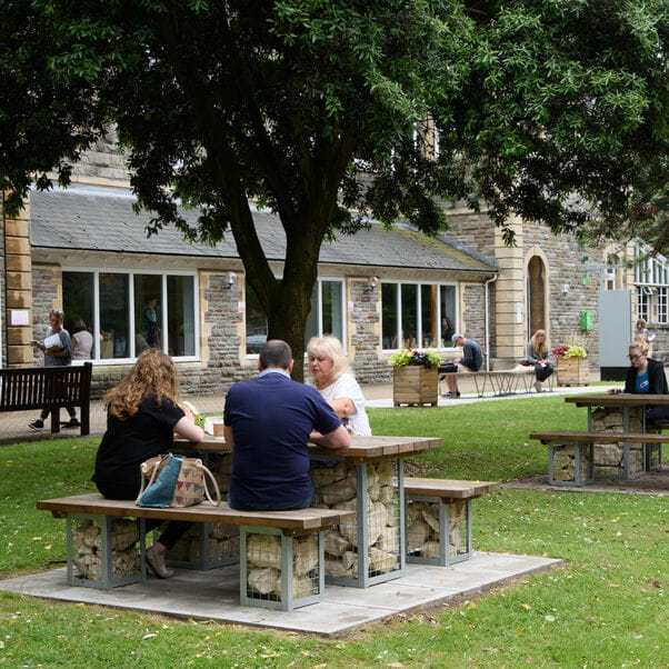 UWE Bristol staff enjoying lunch on a picnic table outside on campus.