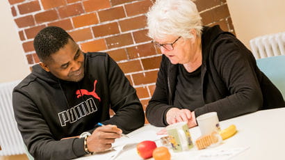 A student talking to a staff member at a table.