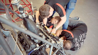 Three students working on a machine