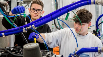 Three students working on a machine