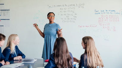 A female teacher in front of a whiteboard, teaching maths