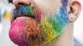 Closeup of someone's beard painted in rainbow colours at Bristol Pride.