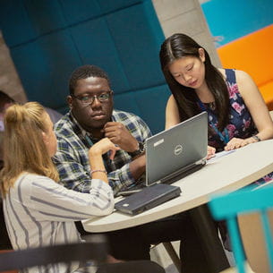 Smartly dressed people sat at a table looking at a laptop.