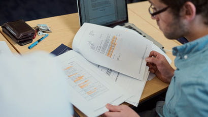 Over the shoulder shot of a student looking through sheets of paper