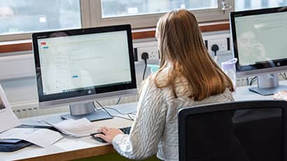 Student at workstation in the library working on a PC.