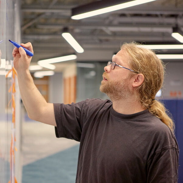 Mathematician writing equations on a whiteboard.