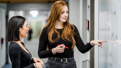 Two people looking at mathematic formulas on a whiteboard. © Tom Sparey, All Rights Reserved.
