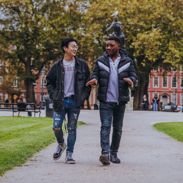 Two male students walking through Queens Square in Bristol City Centre.