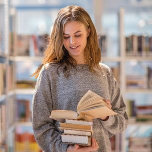 A student browsing through books in a library